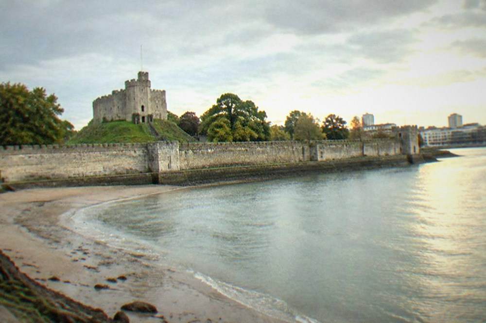 A wide sandy beach curving between limestone cliffs at low tide