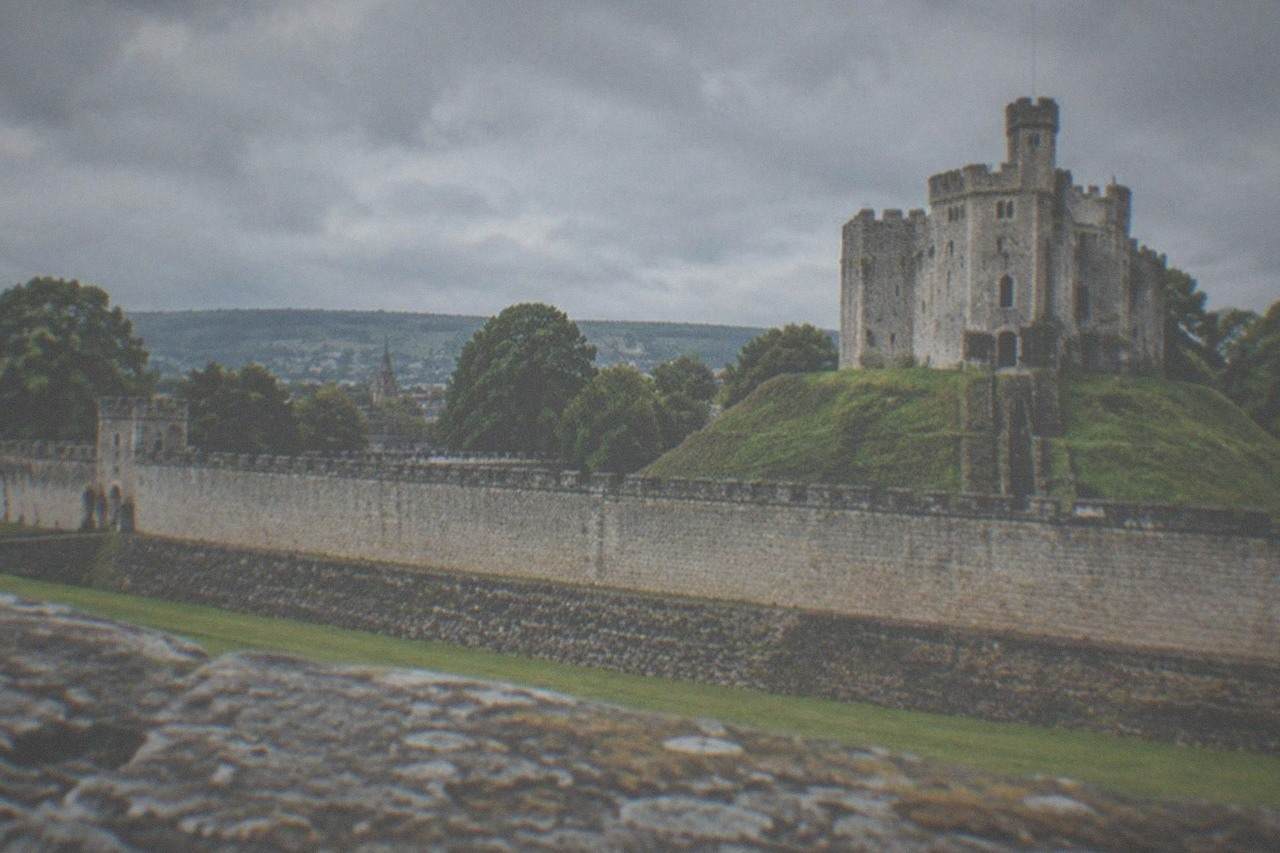 Green hills and a stone castle tower rising above a Welsh valley town