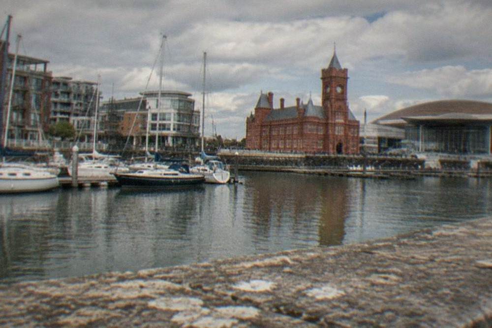 Waterfront buildings around Cardiff Bay on a calm afternoon with boats moored along the quay