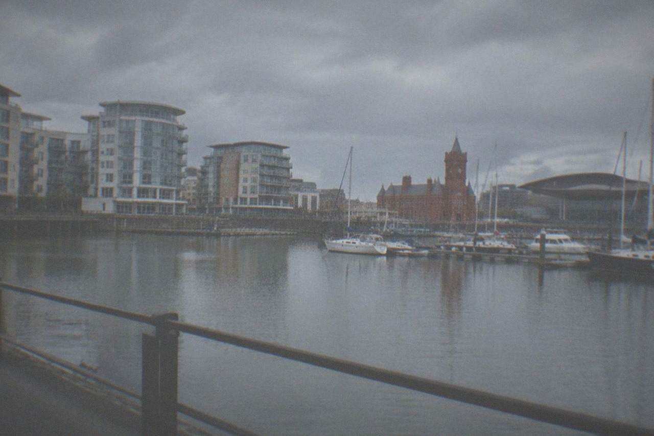 Waterfront buildings around Cardiff Bay on a calm afternoon with boats moored along the quay