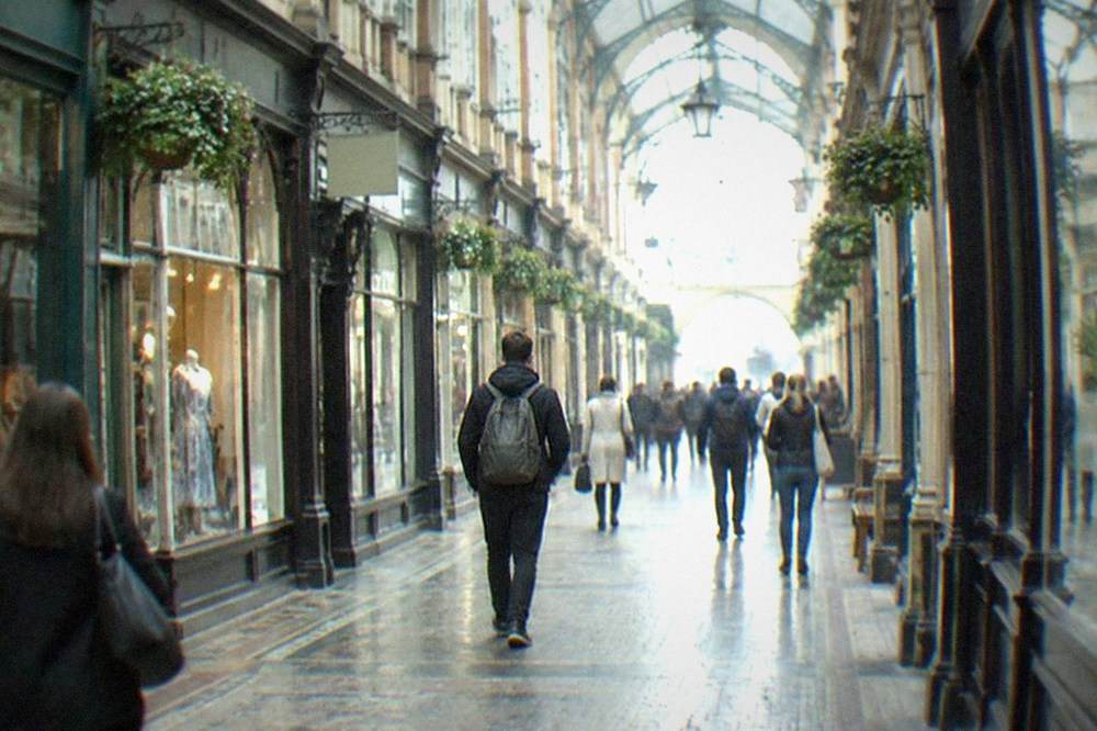Shoppers passing under the glass roofs of a Victorian shopping arcade in Cardiff