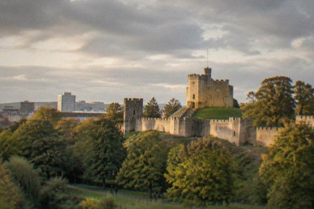Cardiff Castle keep rising above the city skyline with Bute Park greenery in the foreground
