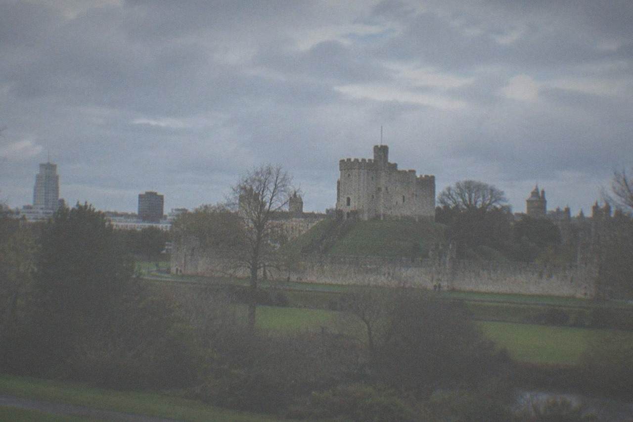 Cardiff Castle keep rising above the city skyline with Bute Park greenery in the foreground