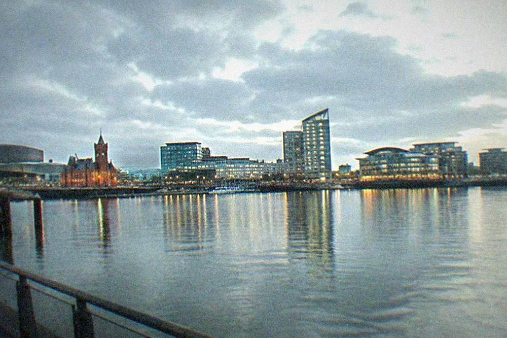 A calm evening view across Cardiff Bay water towards illuminated modern buildings