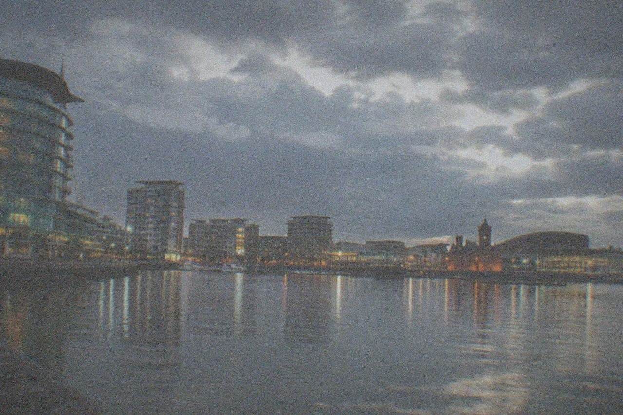 A calm evening view across Cardiff Bay water towards illuminated modern buildings
