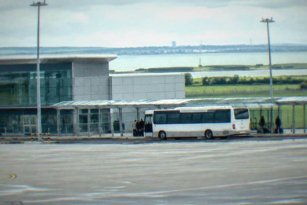 A bus parked at an airport kerbside beside a covered walkway