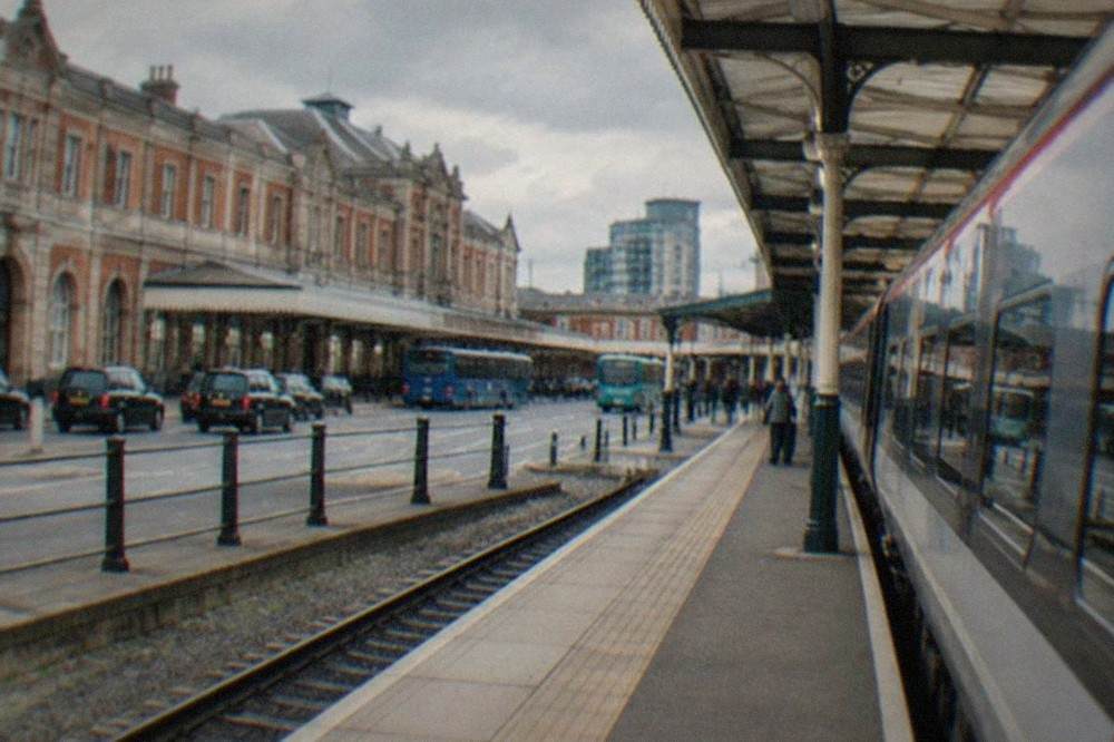 A modern intercity train waiting at a platform beside a station canopy on a bright day
