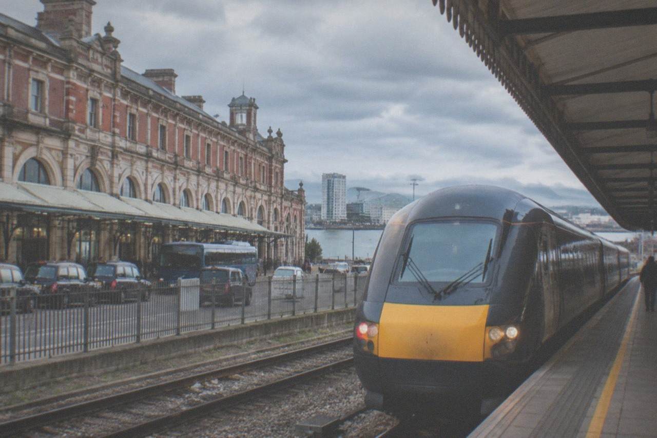 A modern intercity train waiting at a platform beside a station canopy on a bright day