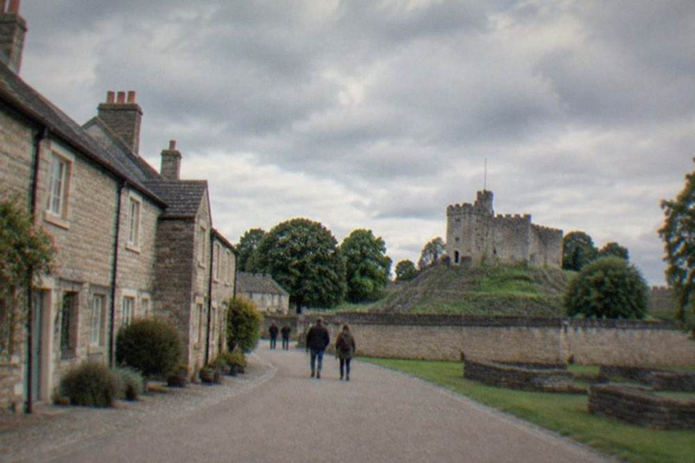 A row of historic stone cottages arranged along a museum village street under a wide sky
