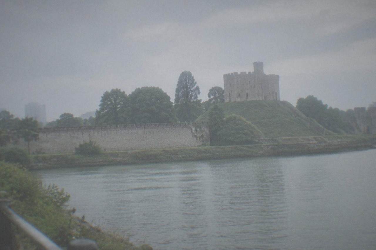 A stone castle keep rising above a green river valley in South Wales