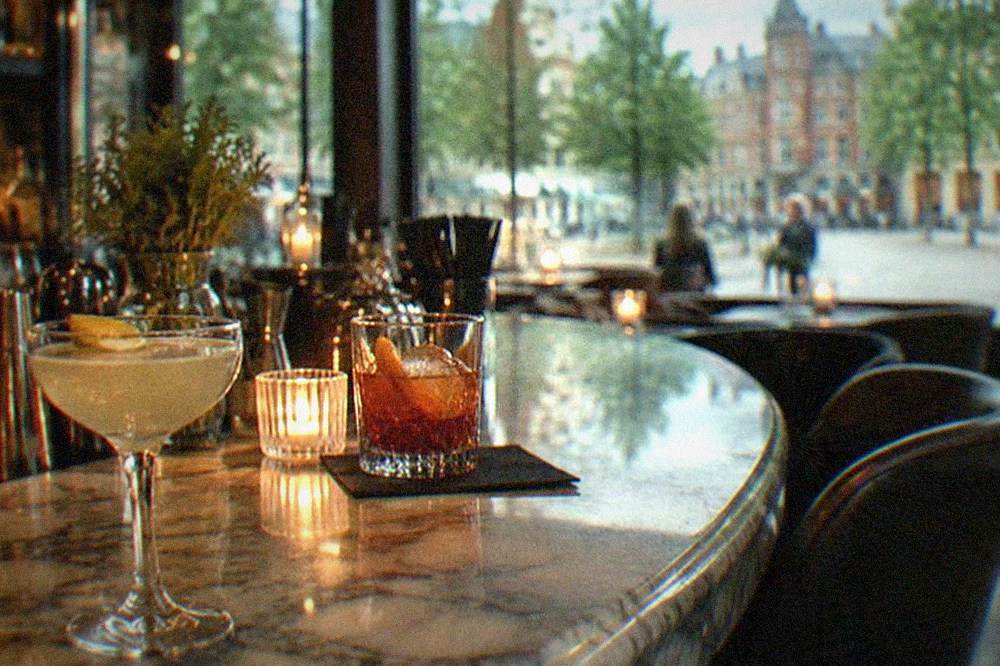 A candlelit cocktail bar with a marble counter, glassware and low lighting