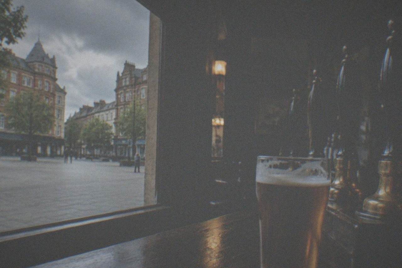 A dimly lit traditional pub interior with wooden bar counter and rows of beer pumps