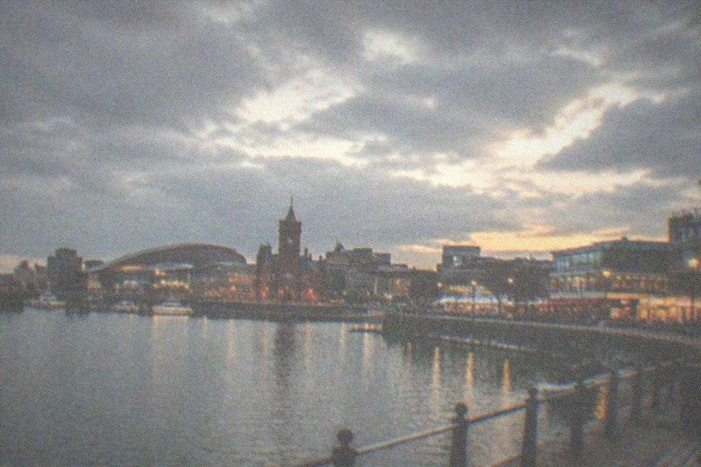 Cardiff Bay waterfront at dusk with street lights and restaurants along the harbour edge
