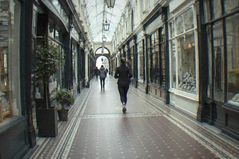 Victorian shopping arcade interior with small shopfronts under a glass roof