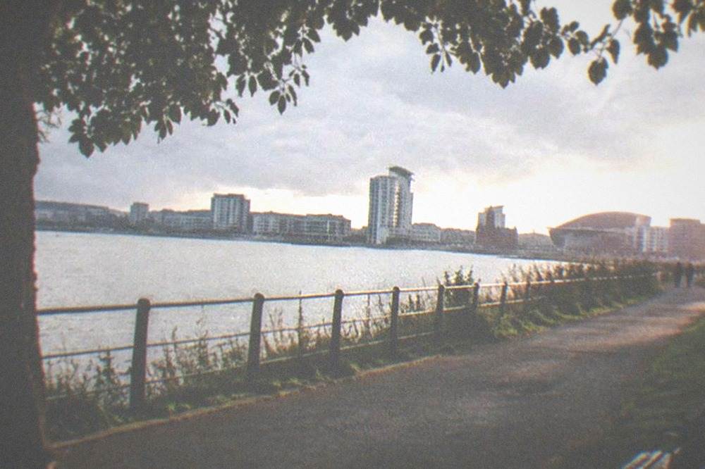 River path beside parkland leading toward a city skyline