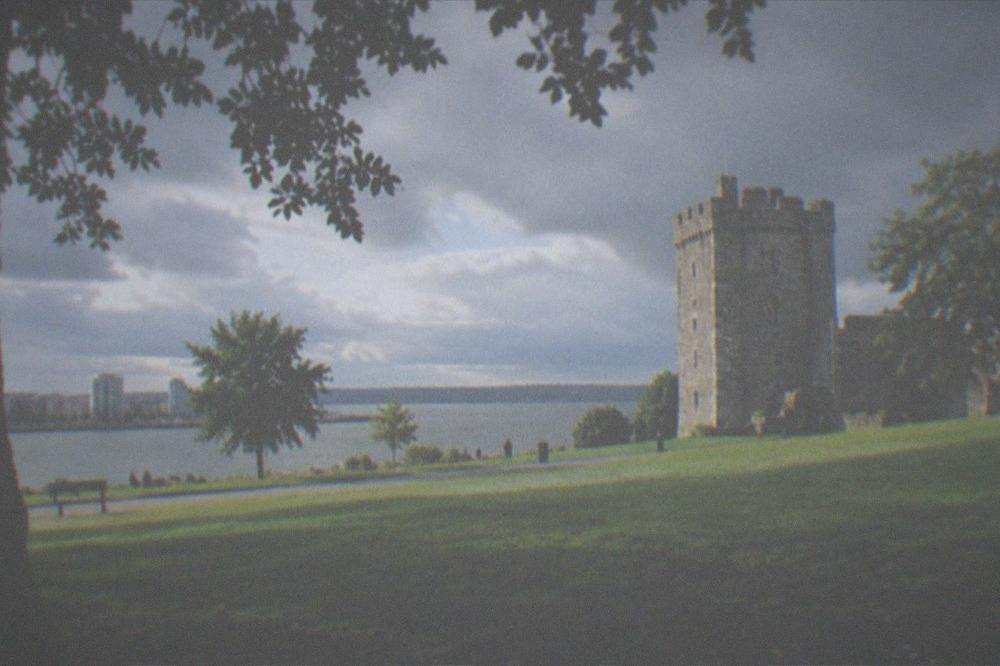 Late afternoon light across a grassy green with a stone tower in the background