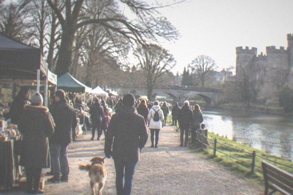 Open-air food stalls and crowds gathered on parkland in daylight
