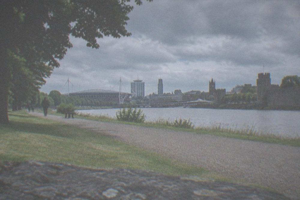 View across a park towards a city skyline with a stadium and civic buildings