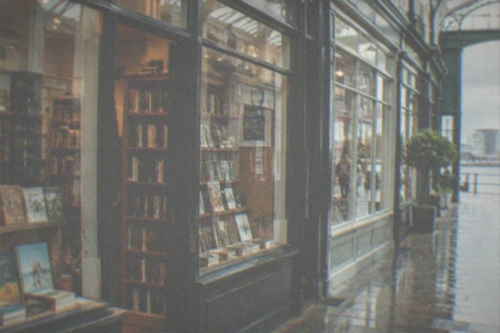 A small independent bookshop front inside a covered arcade with books displayed in the window