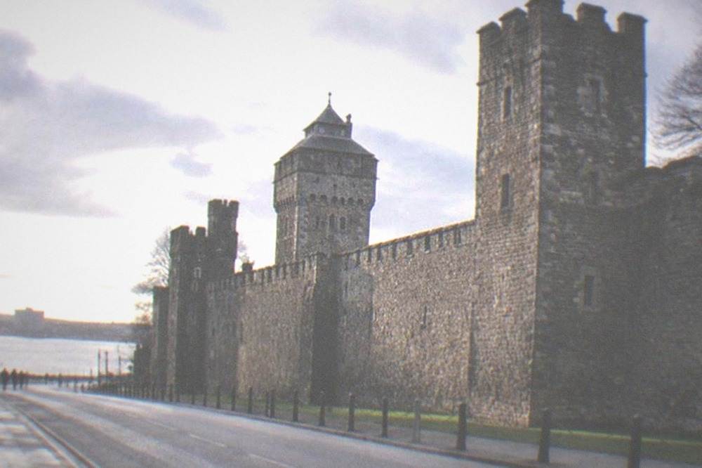 The exterior of Cardiff Castle's stone wall with towers above a city street