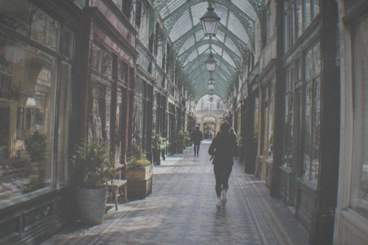 A covered Victorian shopping arcade with ornate ironwork ceiling and small independent shopfronts
