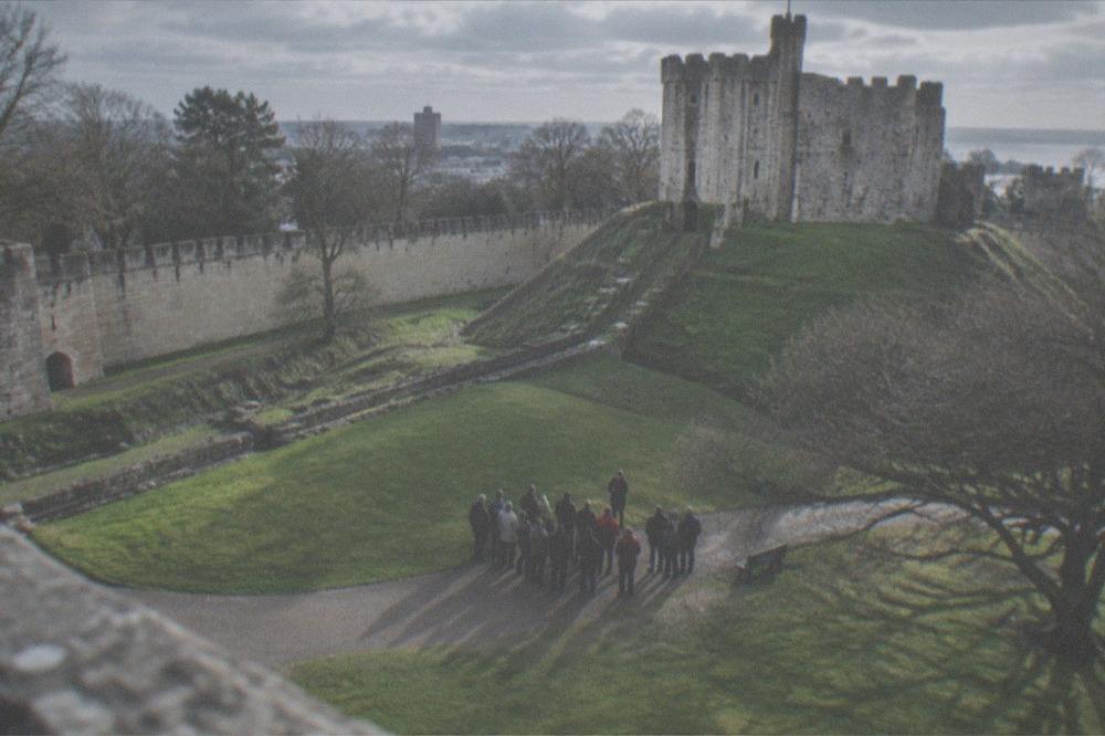 A guided tour group gathered on the castle grounds near the keep