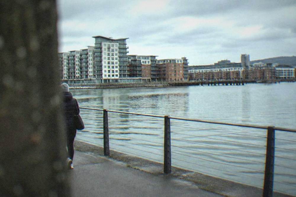 A flat waterside path beside the Cardiff Bay waterfront with apartment buildings and a calm channel