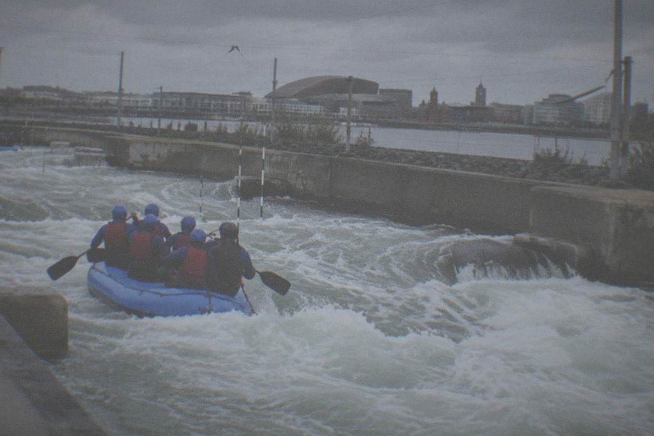 A white water rafting course with foaming rapids between concrete banks under an overcast sky