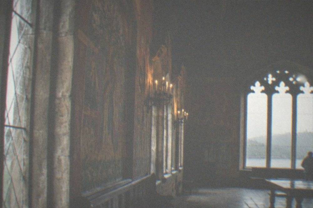 A stone banqueting hall with painted walls and a timber vaulted ceiling