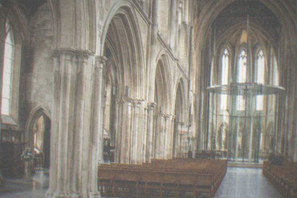 A tall cathedral interior with stone arches and a modern central structure