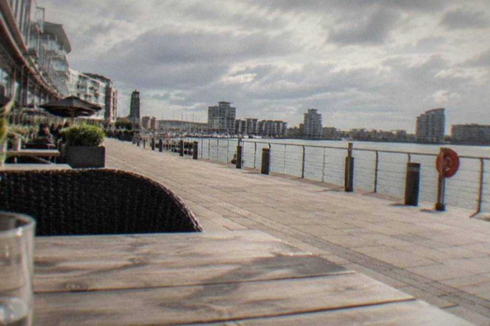 Waterfront boardwalk with restaurants and apartments along a calm bay
