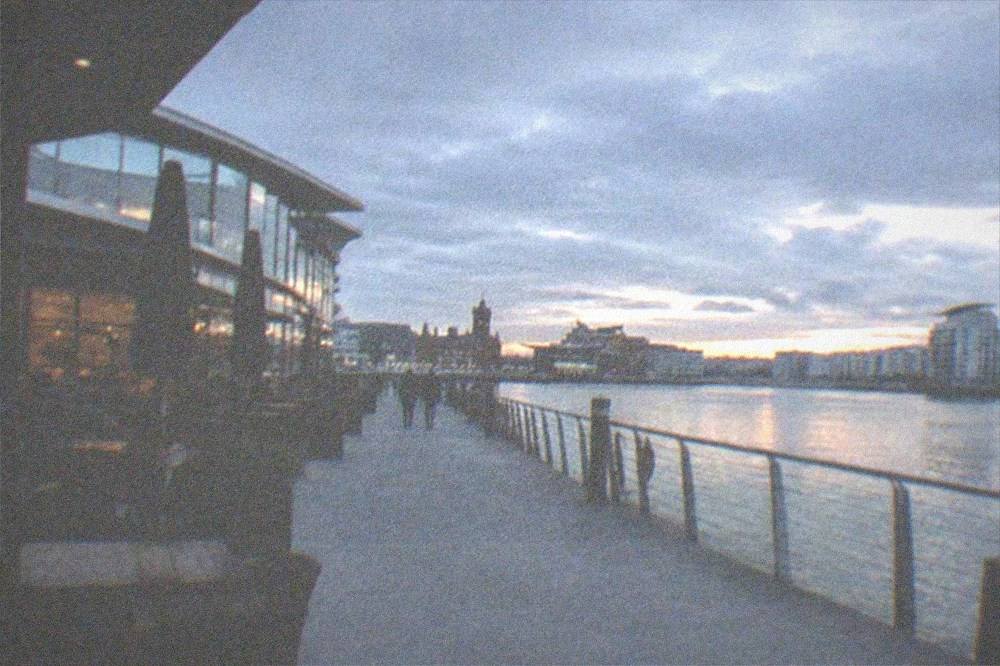 Modern station concourse with a train at the platform beside a waterfront