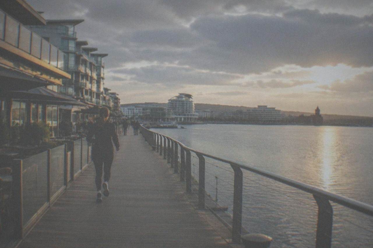 Waterfront boardwalk with restaurants and apartments along a calm bay