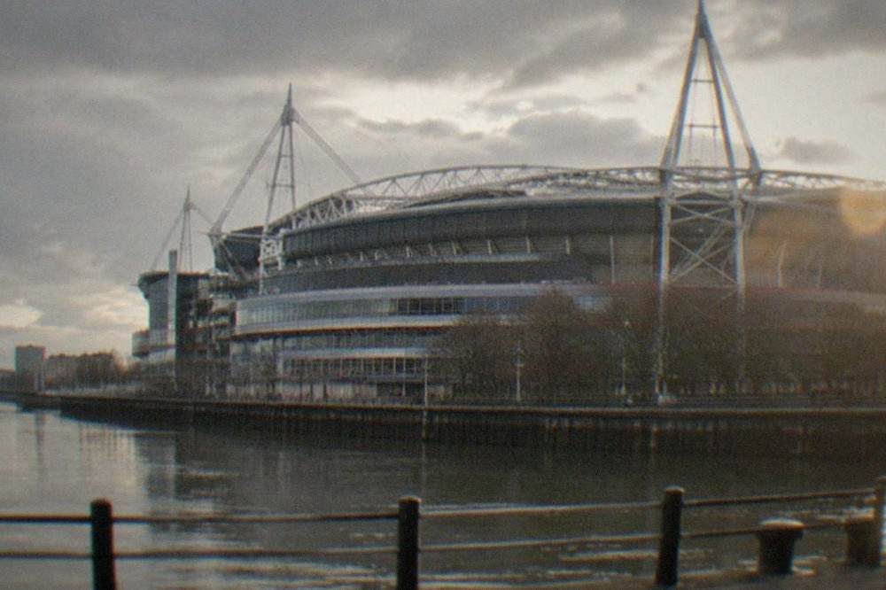 A large modern stadium with a retractable roof seen from outside on a bright day