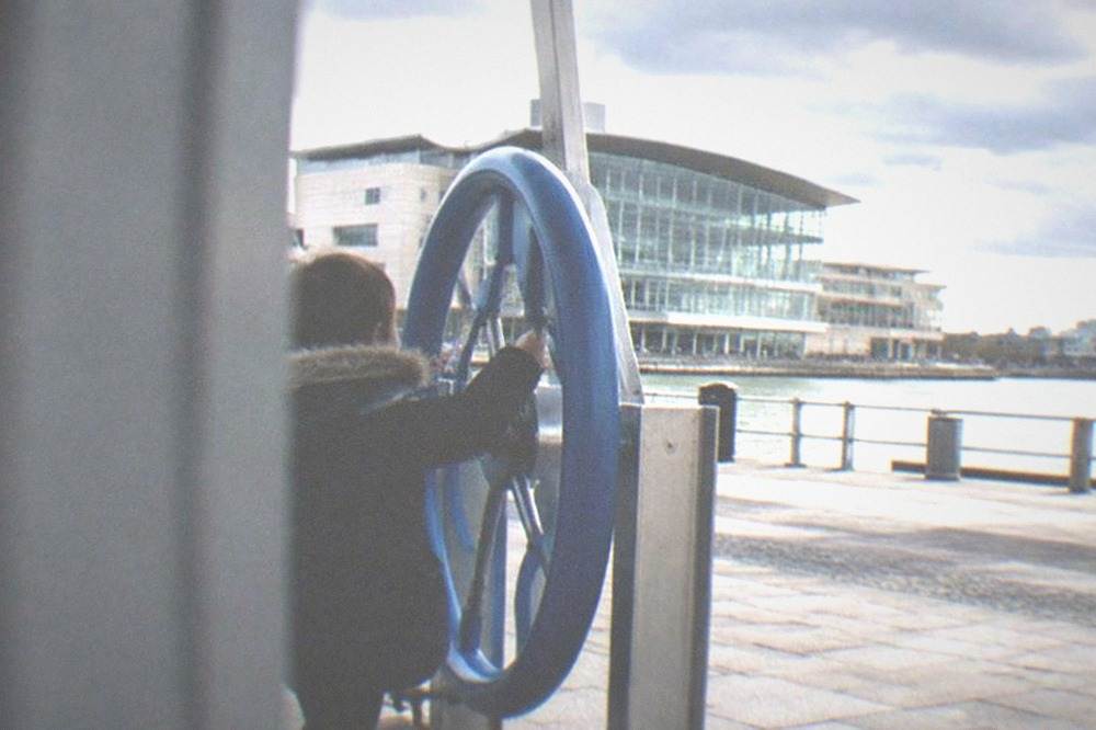 Child turning a large wheel mechanism on a bright interactive science exhibit