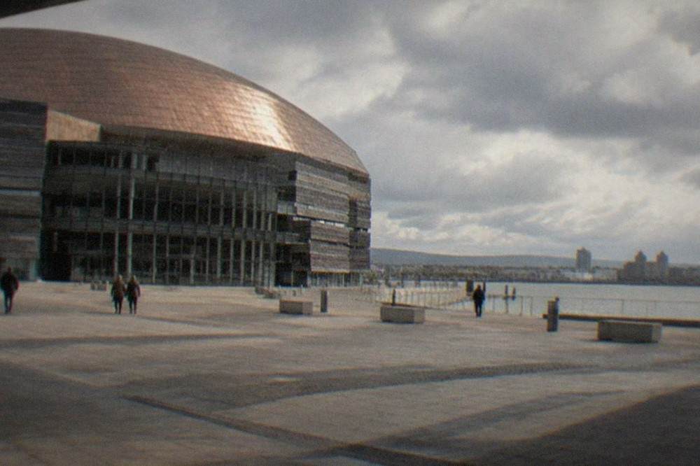 A wide plaza in front of a large arts centre with water beyond