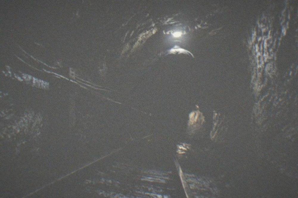 Underground mine tunnel lit by a single lamp on a safety helmet