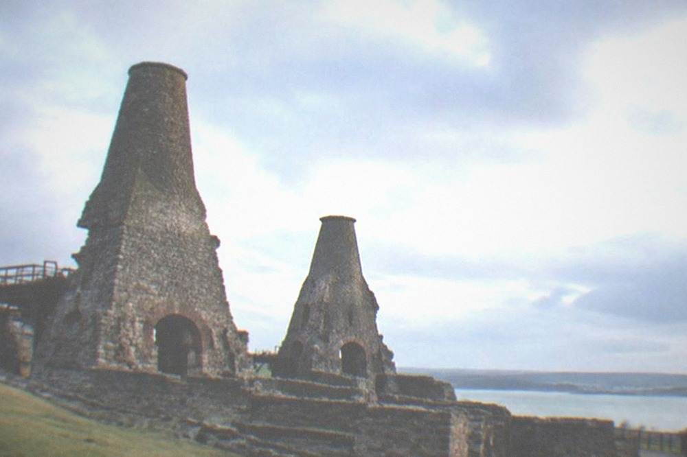 Ruined stone blast furnaces of an old ironworks under a wide sky