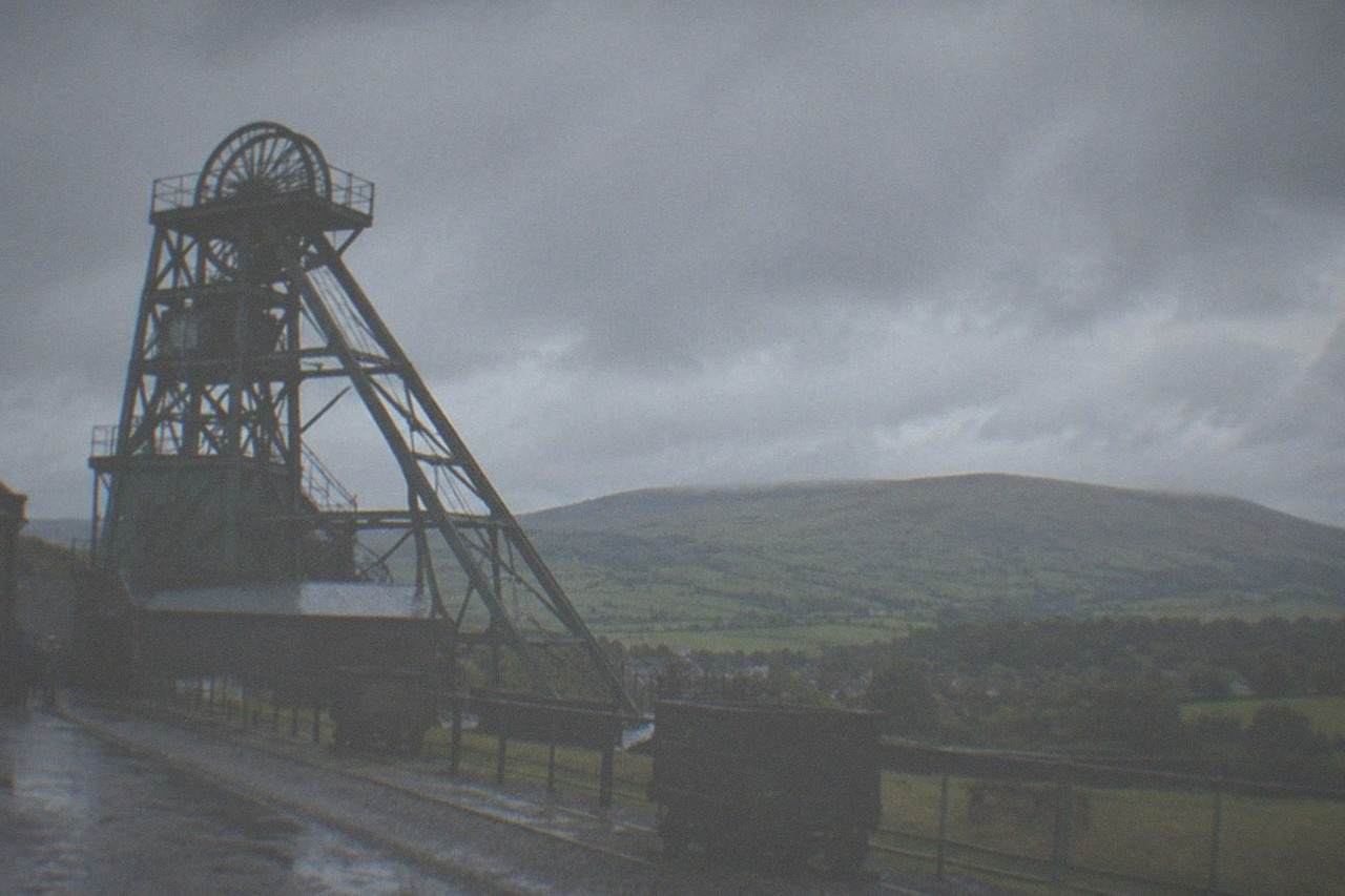 Winding tower of a former coal mine above green hills at Blaenavon