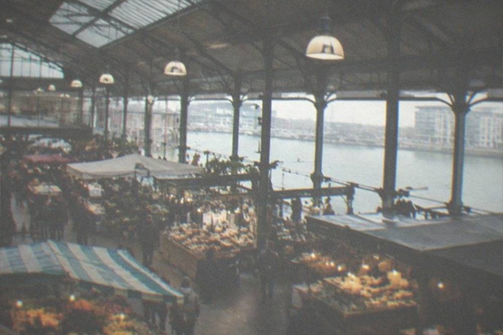 A covered market hall with food stalls and hanging lights