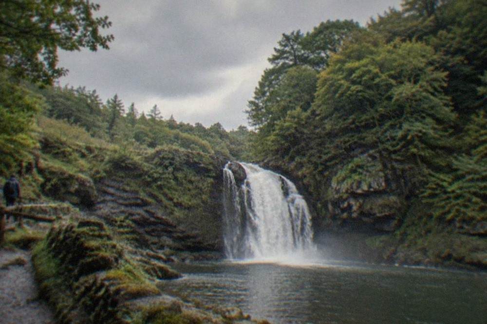 A waterfall plunging through a wooded gorge in South Wales