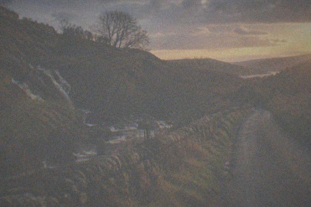 A narrow rural lane winding through a Welsh valley at dusk