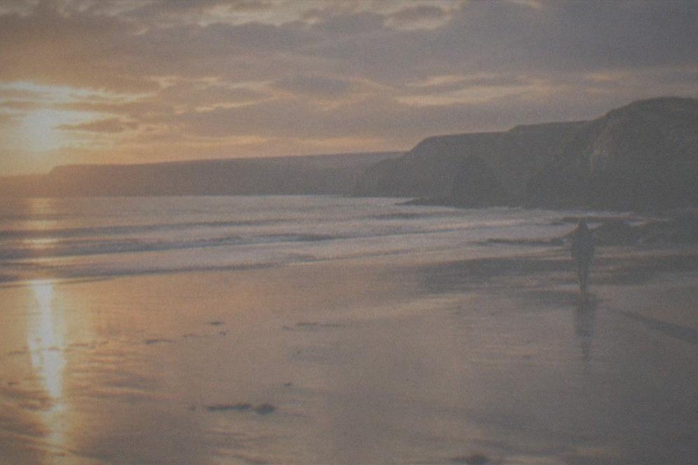 Empty beach at golden hour with long shadows across wet sand