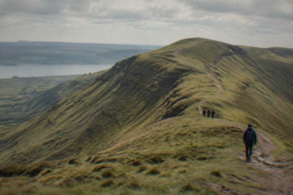 A grassy mountain ridge rising above open moorland under a wide sky