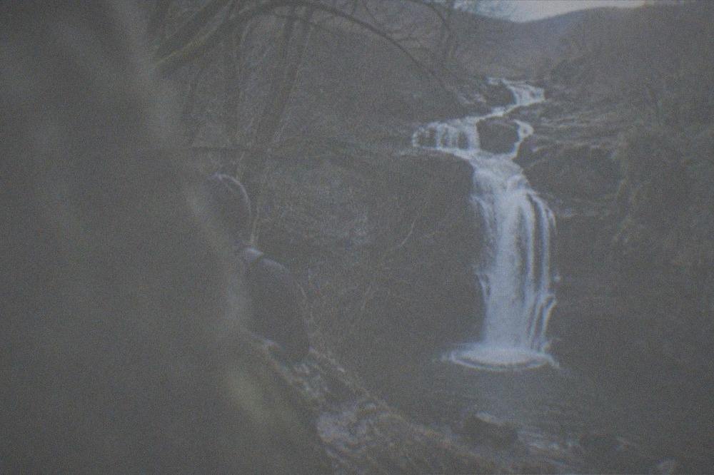 A waterfall cascading into a rocky wooded gorge