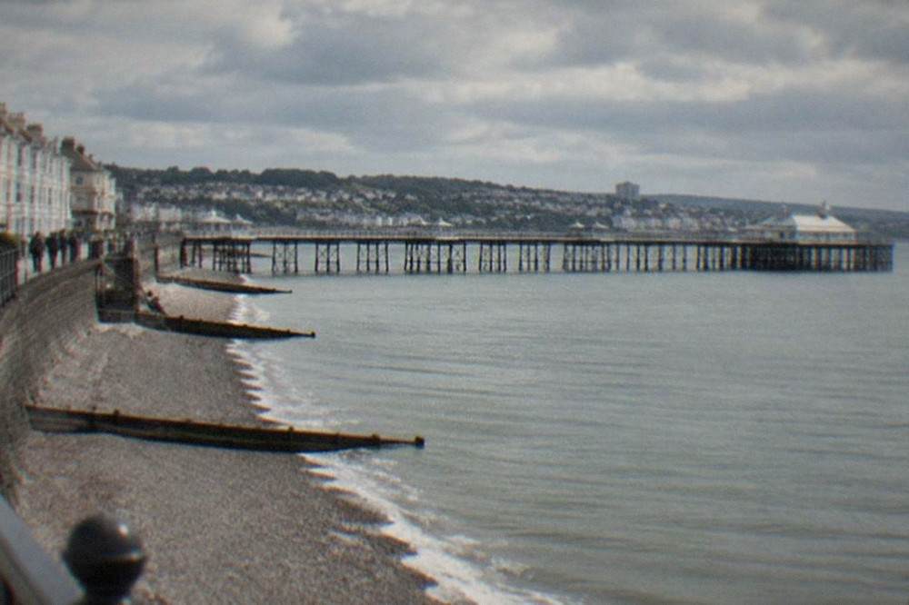 A long Victorian pier extending into a wide estuary with a town behind it