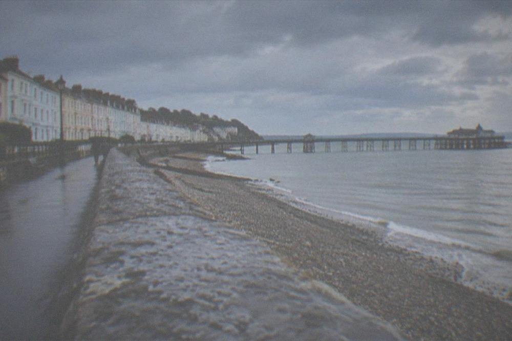 A paved path along a sea defence wall with open water on both sides