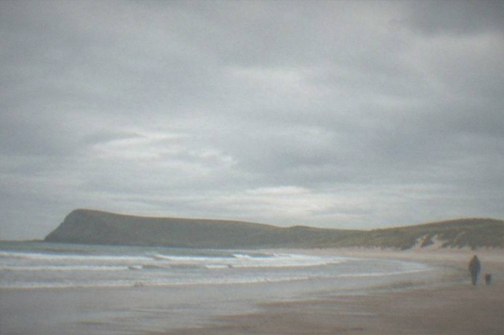 Empty sandy beach with waves rolling in and dunes behind