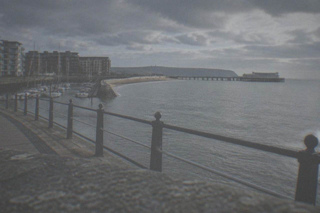 A seaside promenade curving along a bay with a Victorian pier in the distance