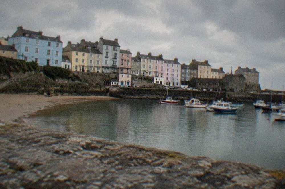 Pastel coloured Georgian houses rising above a sandy beach beside a small harbour